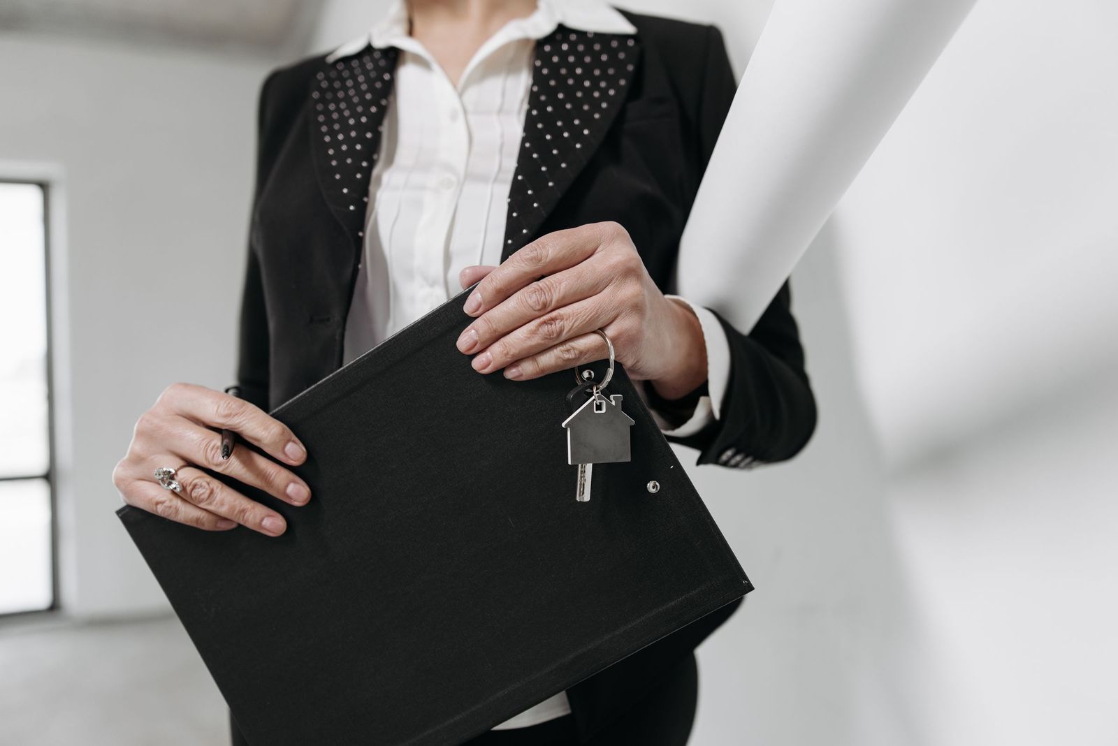 Real estate professional holding a folder and a house-shaped keychain